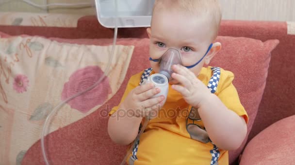 The kid himself holding a mask from an inhaler and breathes the medicine at home. Treats inflammation of the airways via nebulizer. Preventing asthma and cough. — Stock Video