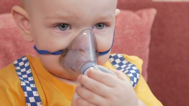 El propio niño sostiene una máscara de un inhalador y respira el medicamento en casa. Trata la inflamación de las vías respiratorias a través del nebulizador. Prevención del asma y la tos . — Vídeos de Stock