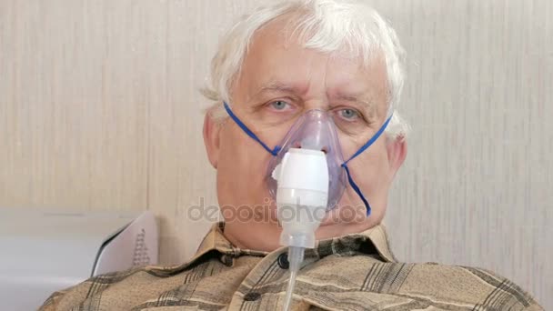 Um idoso segurando uma máscara de um inalador em casa. Trata a inflamação das vias aéreas via nebulizador. Prevenir asma e tosse. Close-up . — Vídeo de Stock