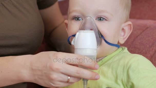 Mother holds the mask on the baby inhaler and breathes the medicine at home. Treats inflammation of the airways via nebulizer. Preventing asthma and cough — Stock Video