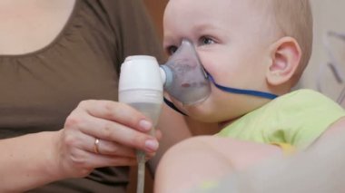 Anne bebek inhaler maske tutar ve evde ilaç nefes. Nebulizatör ile solunum yolları iltihabı davranır. Astım ve öksürük önlenmesi