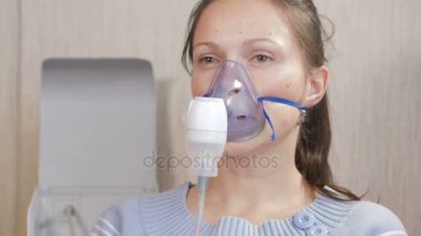 Astım bir maske evde tutan genç kadın. Nebulizatör ile solunum yolları iltihabı davranır. Astım ve öksürük önlenmesi