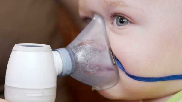 La madre sostiene la máscara en el inhalador del bebé y respira el medicamento en casa. Trata la inflamación de las vías respiratorias a través del nebulizador. Prevención del asma y la tos — Vídeos de Stock