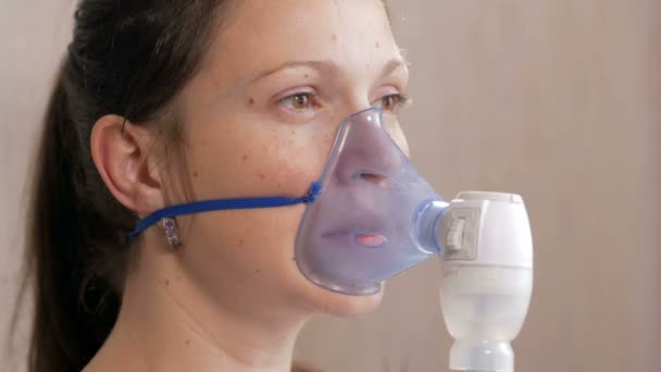 Une jeune femme tenant un masque d'un inhalateur à la maison. Traite l'inflammation des voies respiratoires via un nébuliseur. Prévenir l'asthme et la toux — Video
