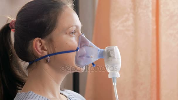 Νεαρή γυναίκα που κρατάει στο σπίτι μια μάσκα από μια συσκευή εισπνοής. Αντιμετωπίζει τη φλεγμονή των αεραγωγών μέσω νεφελοποιητή. Πρόληψη του άσθματος και βήχα — Αρχείο Βίντεο
