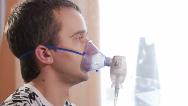 Jeune homme tenant un masque d'un inhalateur à la maison. Traite l'inflammation des voies respiratoires via un nébuliseur. Prévenir l'asthme et la toux — Video