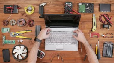 Adam laptop onarım için döner. Yavaşça içeri alır. Ahşap masa üstü görünümü.