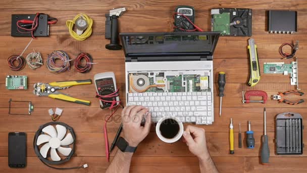 Ingeniero masculino trabajos de reparación de computadoras con portátil desmontado. Uno puede ver la placa base de las computadoras. Mesa de madera vista superior — Vídeos de Stock