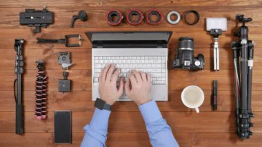 Eller fotoğrafçı adam ahşap masa laptop ile çalışıyorum. Yukarıdan görüntüleyin. Masaya vurduğu için aksesuarları vardır
