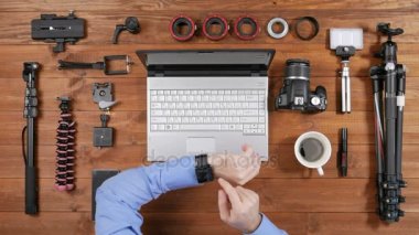 Eller erkek fotoğrafçı smartwatch bir tahta masada iletileri denetleyin. Yukarıdan görüntüleyin. Masaya vurduğu için aksesuarları vardır