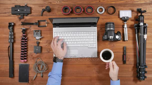 Hands male photographer copy pictures from the camera to the laptop. Wooden table top view. Presses computer keys, pulls flash card out of the computer, insert the camera. — Stock Video