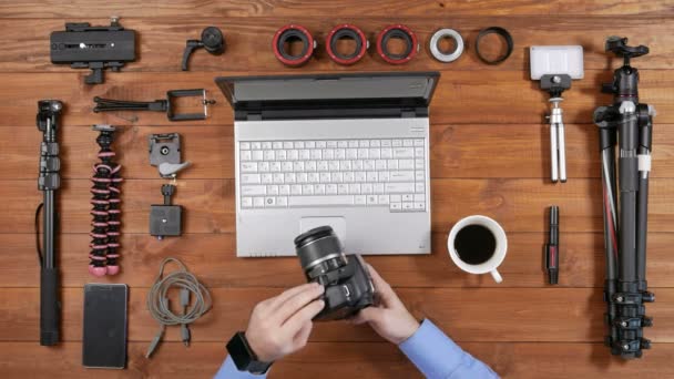 Mãos fotógrafo masculino copiar fotos da câmera para o laptop. Mesa de madeira vista superior. Insira o fio na câmera e espera — Vídeo de Stock