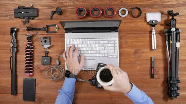 Mãos fotógrafo masculino copiar fotos da câmera para o laptop. Mesa de madeira vista superior. Esperando e, em seguida, puxa o fio da câmera — Vídeo de Stock