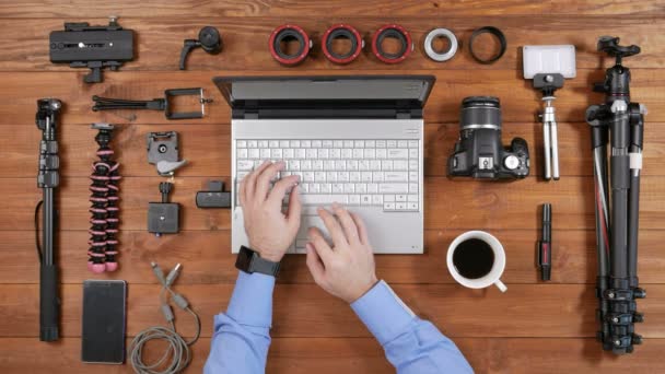 Manos fotógrafo masculino copiar imágenes de la cámara a la computadora portátil. Vista superior de mesa de madera. Presiona las teclas del ordenador, saca la tarjeta flash del ordenador, inserta la cámara . — Vídeos de Stock