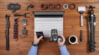 Eller erkek fotoğrafçı fotoğraf makinesi telefon ile bağlayın. Ahşap masa üstü görünümü. Wifi fotoğraf makinesi ayarlarını denetleyin