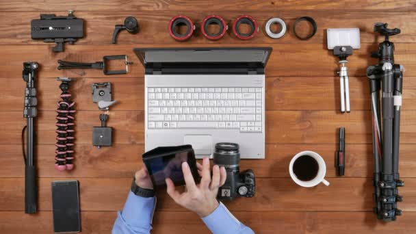 Připojte se ruce mužské fotograf s fotoaparát tabletu. Dřevěný stůl horní pohled. Zkontrolovat nastavení fotoaparátu pro wifi — Stock video