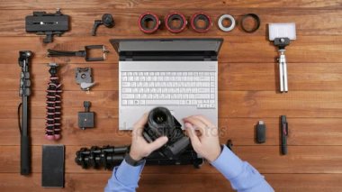 Eller erkek fotoğrafçı bir tripod üzerinde kamera giymek. Ahşap masa üstü görünümü. Masaya çekim için donatım