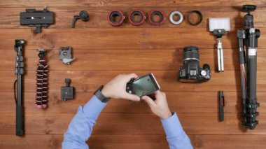 Erkekler fotoğrafçı selfie telefon ile küçük bir tripod üzerinde yapar. Ahşap masa üstü görünümü. Masaya çekim için donatım