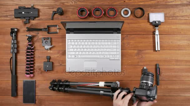 Manos fotógrafo masculino retiró la cámara del trípode. Vista superior de mesa de madera. Equipo para disparar sobre la mesa — Vídeos de Stock