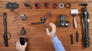 Eller fotoğrafçı adam selfie için esnek bir tripod üzerinde telefon koymak. Ahşap masa üstü görünümü. Masaya çekim için donatım