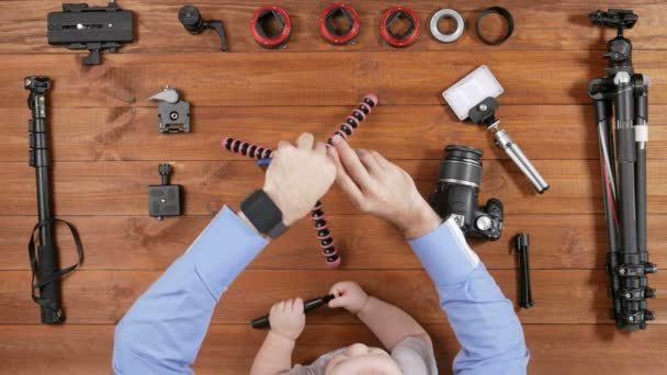 Fotograf Vater mit einem kleinen Sohn machen Selfie-Telefon. Holztischplatte Ansicht. Das Kind spielt mit einer Bürste zum Putzen. Ausrüstung für das Schießen auf den Tisch. — Stockvideo