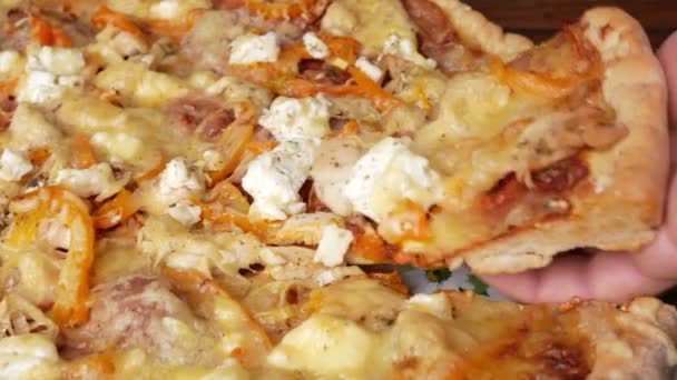 Мужская рука берет кусок домашней пиццы с различными сырами и помидорами. Передвижная камера — стоковое видео