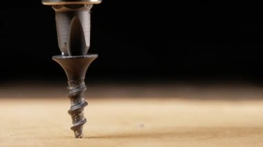 Vida bir elektrikli matkap ahşap yüzey tarafından bükülmüş. Hareketli bir fotoğraf makinesinin yakın çekim. Görünür microcracks ağaç