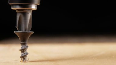 Vida bir elektrikli matkap ahşap yüzey tarafından bükülmüş. Hareketli bir fotoğraf makinesinin yakın çekim. Görünür microcracks ağaç