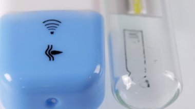 Elektronik termometre beyaz bir masada yatıyor. Kamera kaydırıcıyı hareket. Makro.