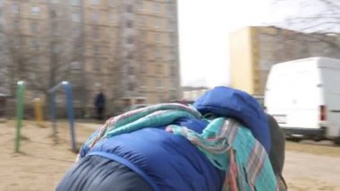 Çekici bir çocuk annesi ile 2 yıldır oyun alanında erken ilkbaharda yürüdüğünü. Bir mavi ceket ve şapka giymiş.