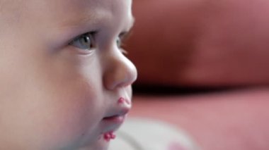 Bir çekici çocuk 2 yaşında bir kırmızı pancar salatası yiyor. Yüz püresi ile sürülür. Masaya oturur. Yakın çekim