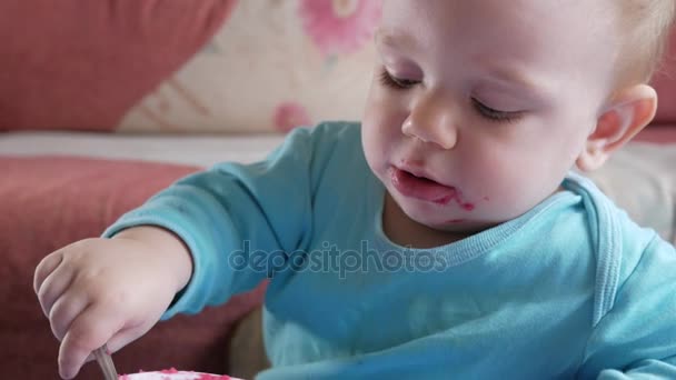 Привлекательный мальчик 2 года ест салат из красной свеклы. Лицо смазано кашей. Сидит на столе . — стоковое видео