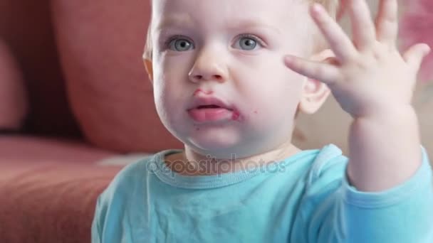 Ein attraktiver Junge im Alter von 2 Jahren isst einen Rote-Rüben-Salat. Das Gesicht ist mit Brei beschmiert. sitzt auf dem Tisch. — Stockvideo