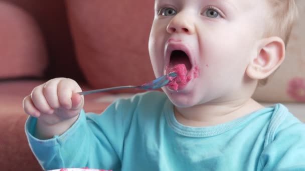 Bir çekici çocuk 2 yaşında bir kırmızı pancar salatası yiyor. Yüz püresi ile sürülür. Masaya oturur. — Stok video