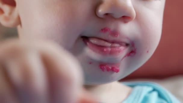 Een aantrekkelijke jongen 2 jaar oud eet een salade van rode biet. Het gezicht is besmeurd met PAP. Zit op de tafel. Close-up — Stockvideo