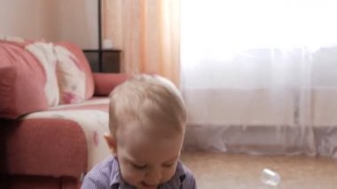 Bir çekici çocuk 2 yıl evde dolaşması ve oyuncak buldozer ile oynarken. O bir ekose gömlek giymiş.