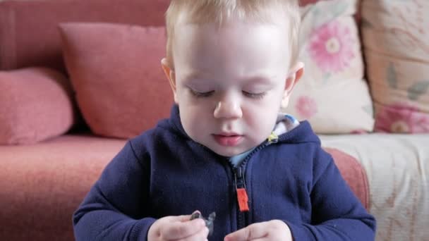 Een aantrekkelijke jongen 2 jaar oud die hij zelf van een multi-gekleurde plasticine thuis aan een tafel mallen. Het blijkt dat een mooie kat. — Stockvideo