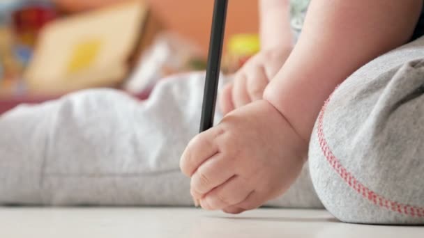 Een aantrekkelijke jongen 2 jaar oud wordt getekend in kleurrijke potloden thuis. Het is zwart in de hand. — Stockvideo