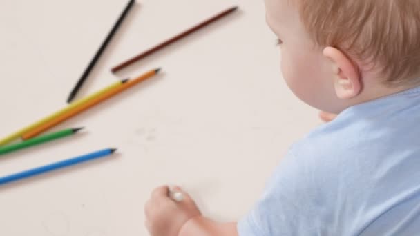 Een aantrekkelijke jongen 2 jaar oud wordt getekend in kleurrijke potloden thuis. Het is zwart in de hand. — Stockvideo