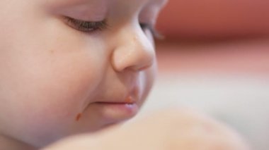 Çekici bir oğlan 2 yaşında kırmızı çorba kendisi yiyor. Kaşık ve sıvı akan eller. Çocuklar sağlıklı beslenme kavramı.