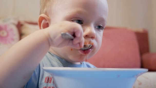 Un beau garçon de 2 ans mange lui-même de la soupe rouge. Cuillère et mains qui coulent liquide. Le concept de saine alimentation des enfants . — Video