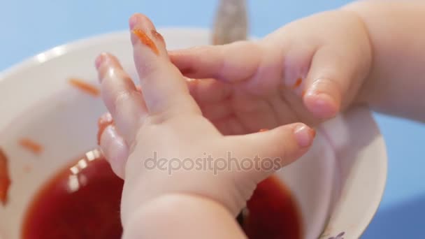 Een aantrekkelijke jongen 2 jaar oude klom in de soep met zijn handen en raakte de ingrediënten met zijn handen. Close-up van vingers. — Stockvideo