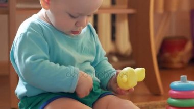 Çekici çocuk evde Plastik ördek ile oynarken 2 yıl. Çocuk ailesiyle konuşuyor. Yakın çekim