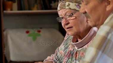 Bir yaşlı çift erkek ve kadın evde onların eski fotoğraflarına bakmaktan ve konuşuyor. Bir bıyık, gözlüklü bir karısı olan bir adam