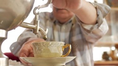 Bir yaşlı çift bir vintage Rus çay semaver çay hazırlar. Bıyıklı bir adam karısı için çay dökülen