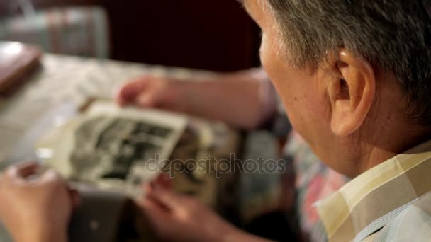 Una pareja de ancianos hombre y mujer están mirando sus viejas fotos en casa y hablando. Un hombre con bigote, una esposa con gafas — Vídeos de Stock