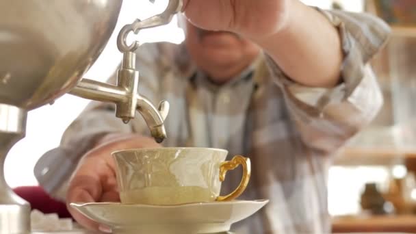 Пожилая пара готовит чай с винтажным русским чайником самоваром. Мужчина с усами наливает чай своей жене — стоковое видео