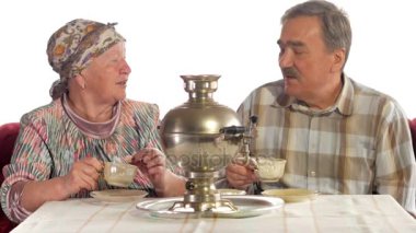 Bir yaşlı çift bir vintage Rus su ısıtıcısı semaver çay içiyor. Eşi bir atkı ile konuşurken bıyıklı bir adam