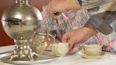 Bir yaşlı çift bir vintage Rus su ısıtıcısı semaver çay içiyor. Eşi bir atkı ile konuşurken bıyıklı bir adam