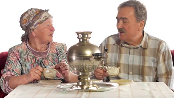 Um casal de idosos está bebendo chá de um samovar de chaleira russo vintage. Um homem com bigode a falar com a mulher num lenço — Vídeo de Stock